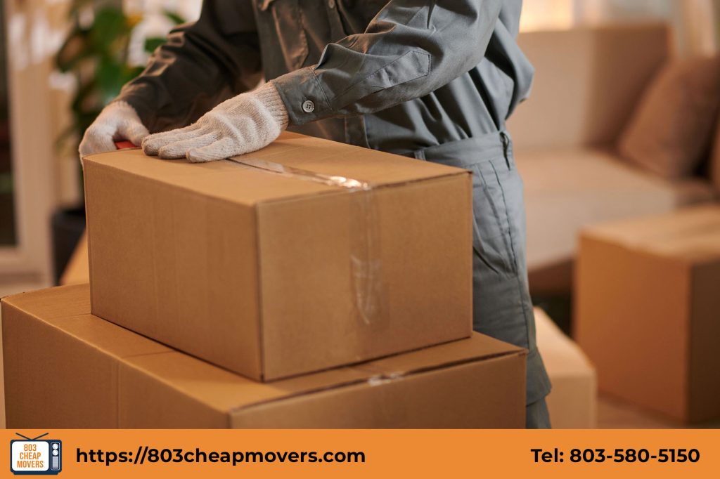 Expert mover securely packing cardboard boxes for a residential house relocation in Forest Acres SC.