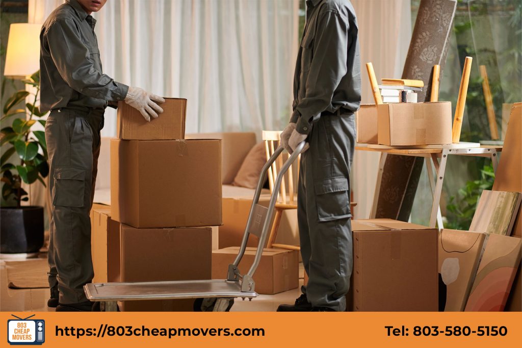 Professional movers using a hand truck dolly to load and move cardboard boxes in Dentsville SC.